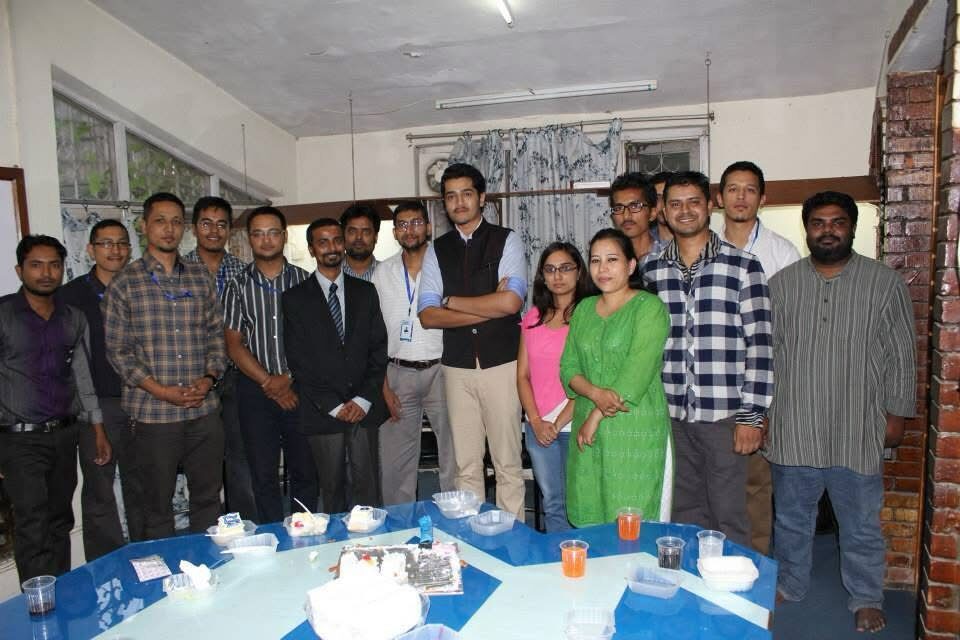 A large group of early team members gathered around a table for a celebration in the first office.